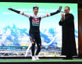 Primoz Roglic feiert den Tagessieg mit seiner typischen „Telemark-Landung“ aus dem Skispringen auf dem Podium.