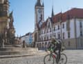 Author Gero Günther bumps across the pavement in front of the Holy Trinity Column and City Hall in Olomouc
