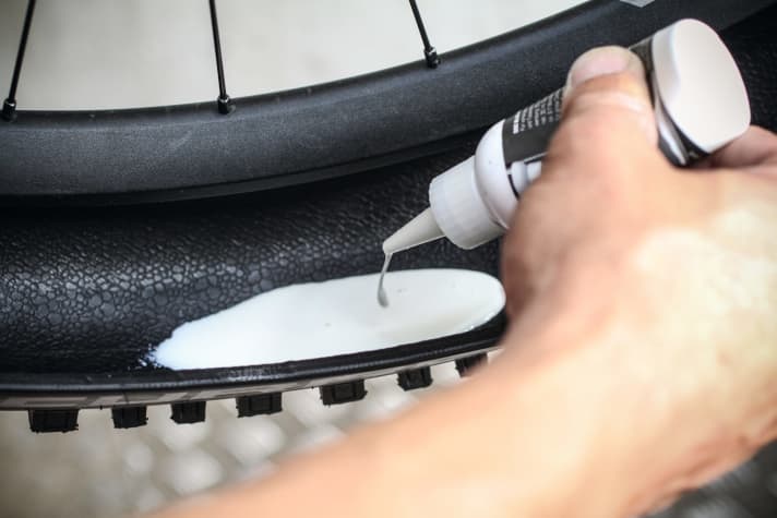   Der direkte Weg: Alternativ zur Spritze oder Flasche kann man die Dichtmilch auch direkt in den Reifen füllen. Dafür den Reifen nur halb-seitig aufziehen und die gewünschte Menge Dichtmilch direkt in den Reifen gießen. Das geht etwas schneller, macht aber oft mehr Dreck. Wir empfehlen daher die erste Methode. Ist die Milch im Reifen, kann der Reifen vollständig aufgezogen werden.