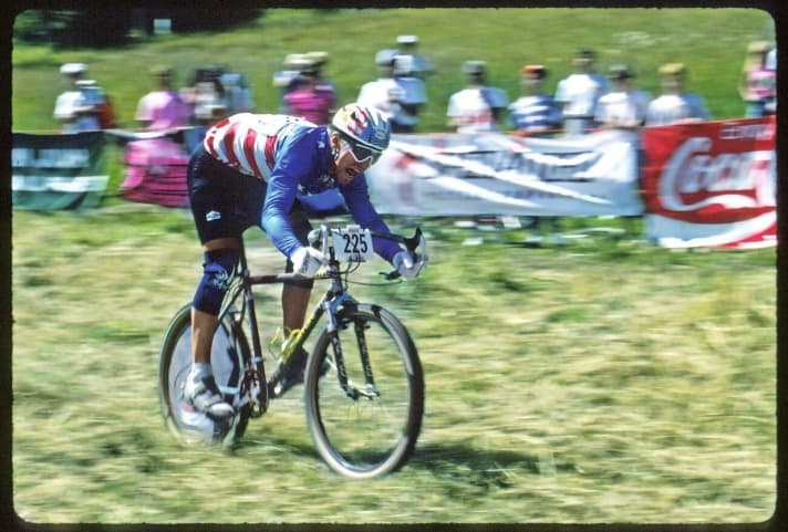   1990: Das wohl ikonischste Motiv der MTB-Geschichte: Superstar John Tomac rast auf seinem C-26 die Downhill-Piste der ersten WM hinab – mit Rennradlenker.