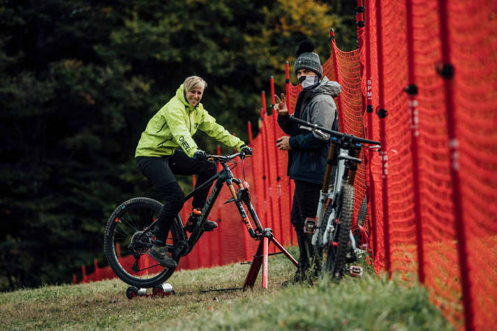   Nina Hoffmann kurbelt sich warm. Ihr Mechaniker (rechts) posiert mit Maske und Victory-Zeichen. Und tatsächlich standen Hoffmann und ihr Downhill-Bike später als today's fastest auf dem Podium. Glückwunsch zum ersten Worldcup-Sieg ihrer noch jungen Rennkarriere.