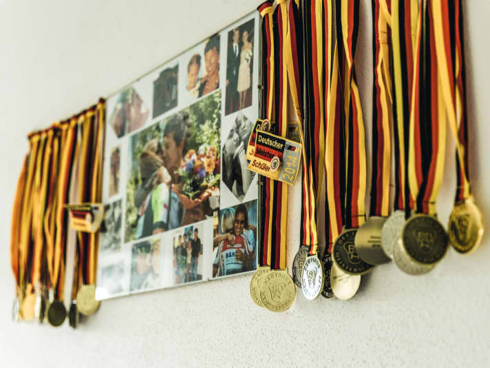Über dem Schreibtisch hängen Medaillen und Fotos aus dem Radsport