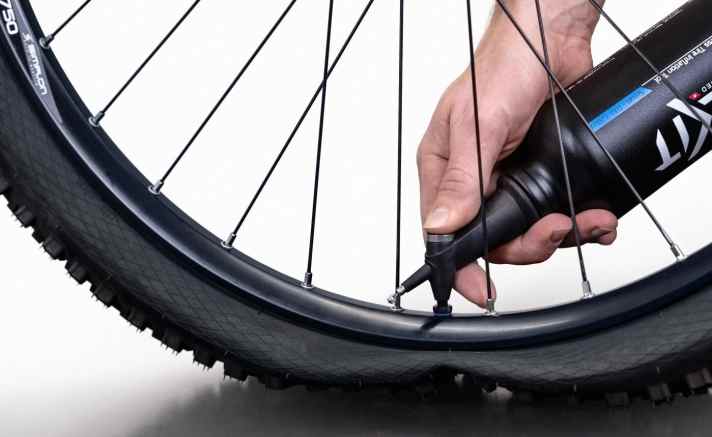   Auch ohne Kompressor kann der Tubeless-Reifen montiert werden. Der <a href="https://www.awin1.com/cread.php?awinmid=11768&awinaffid=471469&clickref=B+Milkit+Tubeless+Booster&ued=https%3A%2F%2Fwww.rosebikes.de%2Fmilkit-tubeless-booster-mobiler-druckspeicher-fur-schlauchlos-reifen-2678308" target="_blank" rel="noopener noreferrer nofollow">Milkit Booster</a> * wird mit der normalen Luftpumpe befüllt und die Luft anschließend schlagartig in den Reifen gestoßen. Besonders praktisch: Der Milkit Booster kann auch als Trinkflasche genutzt werden. 
