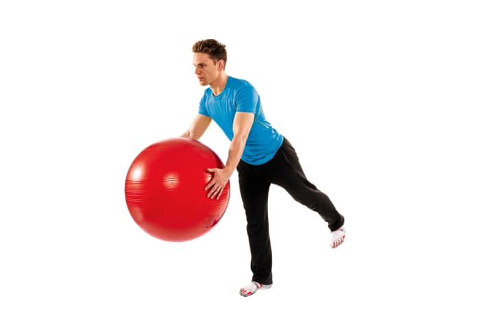   Waage mit Ball: 1. Stehen Sie gerade. Die Füße schulterbreit. Die Hände umfassen den Ball, der etwa auf Beckenhöhe gehalten wird. Heben Sie Ihr linkes Bein ab. Das Standbein ganz leicht gebeugt. 