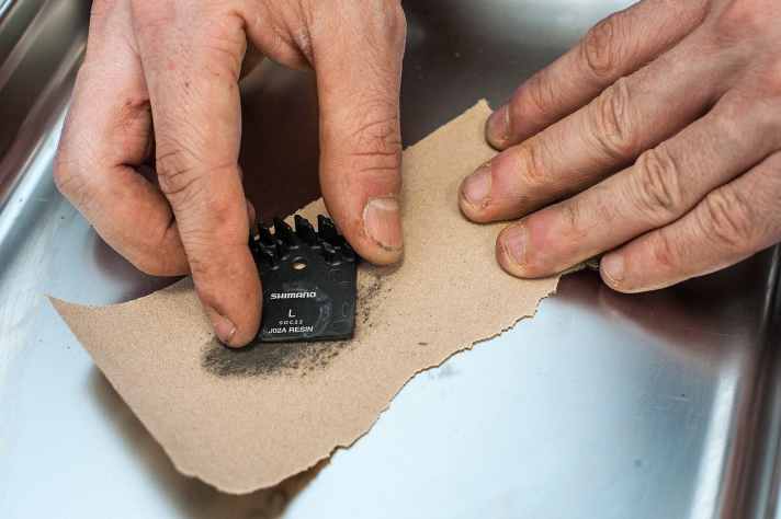 ABSCHLEIFEN: Nachdem ich die Beläge ordentlich mit Schleifpapier bearbeitet hatte, ging es erneut raus auf die Teststrecke. Die Bremsleistung war tatsächlich minimal besser. Allerdings nur minimal. Denn, egal wie fest ich zudrückte, ein Blockieren des Hinterrades war schlicht nicht möglich. Ins Gelände würde ich mich so immer noch nicht wagen.
