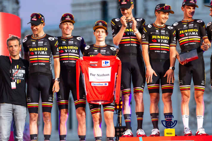 Jumbo-Visma beendete die Vuelta Espana 2023 nicht nur auf den ersten drei Plätzen in der Gesamtwertung im Einzel, sondern damit auch als bestes Team. Bei der Siegerehrung in Madrid präsentierte das Team ein Trikot als Hommage für Nathan Van Hooydonck.