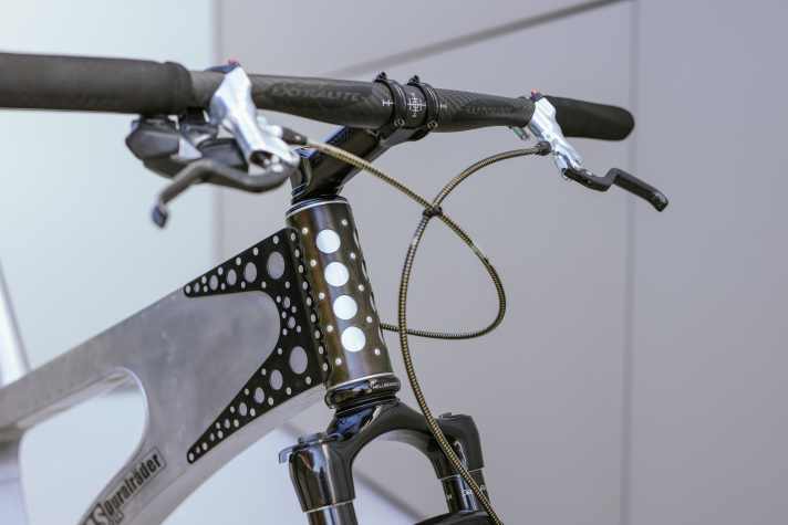 Die gelochte, dunkle Manschette verbindet das Steuerrohr aus Stahl mit dem Rest des Rahmens, der komplett aus Alu-Blech gefertigt ist. Foto: Adrian Vesenbeckh