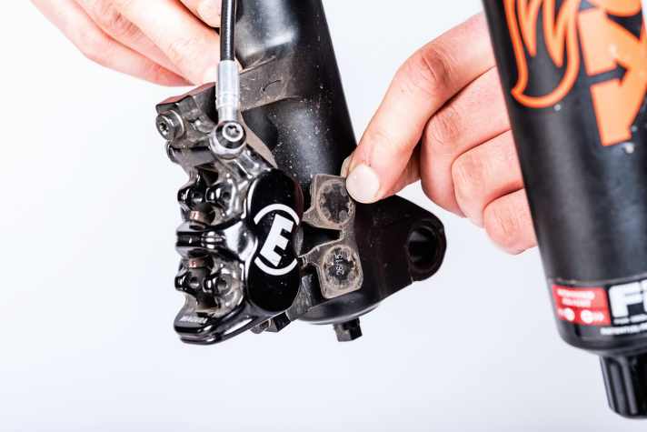    3 Beläge entnehmen: Lassen sich die magnetisch gehaltenen Beläge in diesem Moment nicht leicht entnehmen, sind die Kolben möglicherweise doch noch nicht weit genug auseinandergedrückt. In diesem Fall wiederholen Sie Vorgang 1, und probieren es erneut. Klappt es immer noch nicht, entnehmen Sie die Bremsbeläge einzeln. 