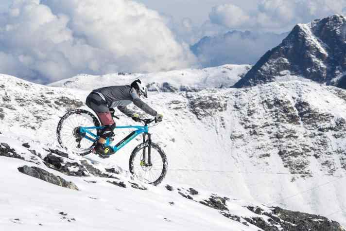    STEIL BERGAB – 80 Prozent der Bremskraft wird übers Vorderrad übertragen – diese Faustregel gilt im Schnee nicht mehr. Je nach Bedingungen bietet das kalte Element zu wenig Traktion, um über das Vorderrad zu verzögern. Also: Je steiler das Gelände, desto vorsichtiger will der vordere Bremshebel bedient werden. Machen Sie statt dessen die Arme lang und verlagern Ihr Körpergewicht deutlich stärker nach hinten, als Sie es von trockenen Bedingungen gewohnt sind. Halten Sie dabei den Lenker locker, und vermeiden Sie allzu starke Lenkbewegungen.