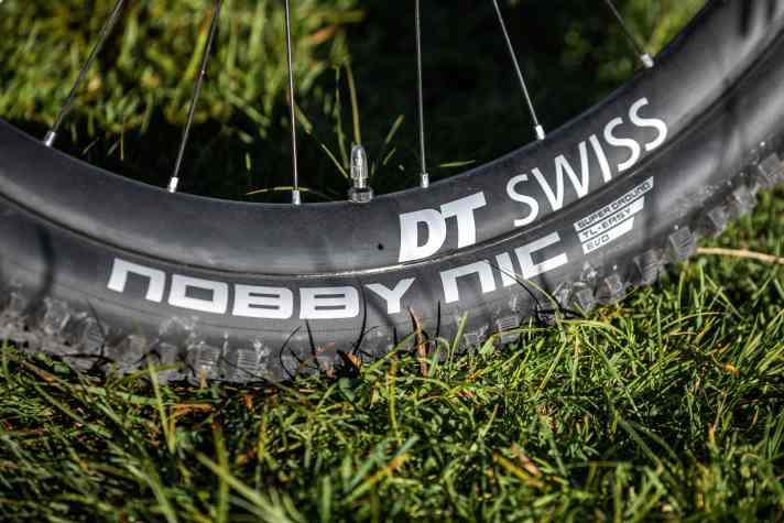   Vor kurzem hätten wir bei dieser Reifenwahl an einem Trail-E-MTB die Hände über dem Kopf zusammengeschlagen. Doch Schwalbe hat dem Nobby Nic eine stärkere Karkasse und dickere Seitenstollen verpasst. Wir sind gespannt, wie er sich im Dauereinsatz schlägt. Mit 2,35 Zoll fällt er recht schmal aus.