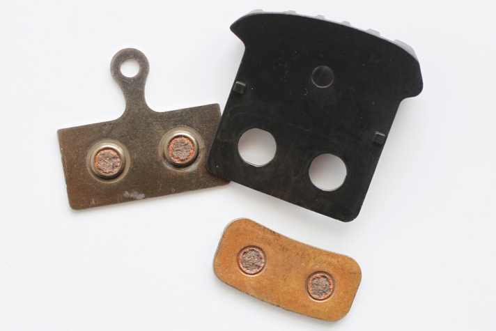   Beim Shimano F03C Belag mit Kühlrippen ist die Trägerplatte zweigeteilt. Eine Aluplatte mit Kühlrippen wird durch eine Stahlplatte auf der Rückseite verstärkt.