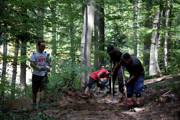   Trailbauprofi Eric (zweiter von links, schwarze Kappe) zeigt wie es geht. Vereinsmitglieder packen mit an, um den neuen Trail in Form zu schaufeln.