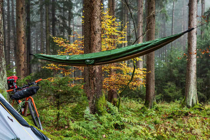Moderne Outdoor- und Reise-Hängematten aus ultraleichten Hightech-Textilien wie die Amazonas Adventure Hammock (Foto) wiegen wenig, nehmen kaum Platz weg und sind ein schnell montiertes, bequemes Bikepacking-Lager.