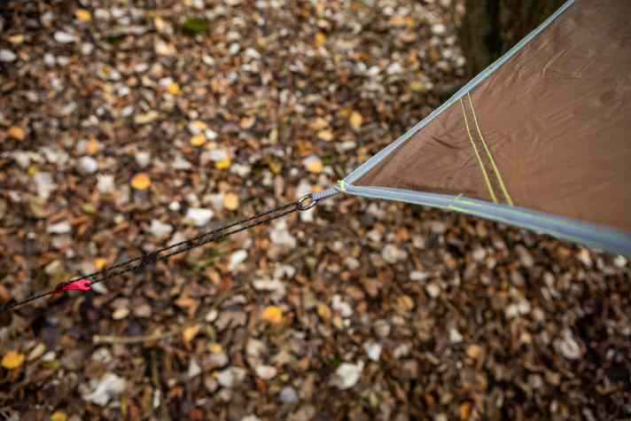 Auch leichte Alu-Heringe sind im Lieferumfang enthalten. Die Spannschnüre bleiben am Tarp und warten in der Ecktasche auf den Einsatz. Die Verarbeitung ist sehr gut. Der umlaufende Saum leitet die Zugkräfte ab. Die roten Alu-Versteller sind robust und bilden den farbigen Kontrapunkt.