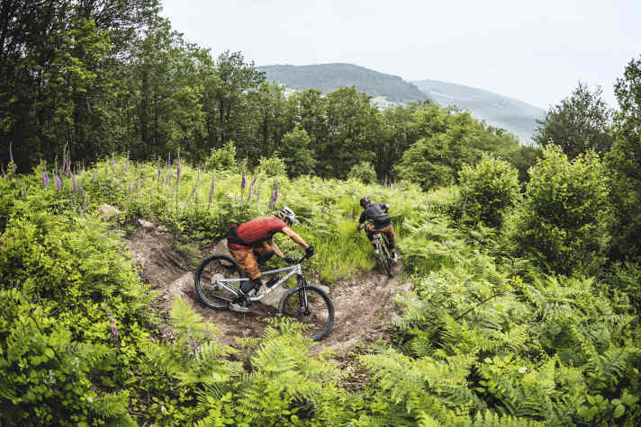 Die Kollegen Peter und Jan scheuchen die Testkandidaten durch die ersten Kurven des Alle-Farben-Trails. Warum alle Farben? 
Die Abfahrt beinhaltet Sektionen aller Schwierigkeitsgrade: blau, rot und schwarz.