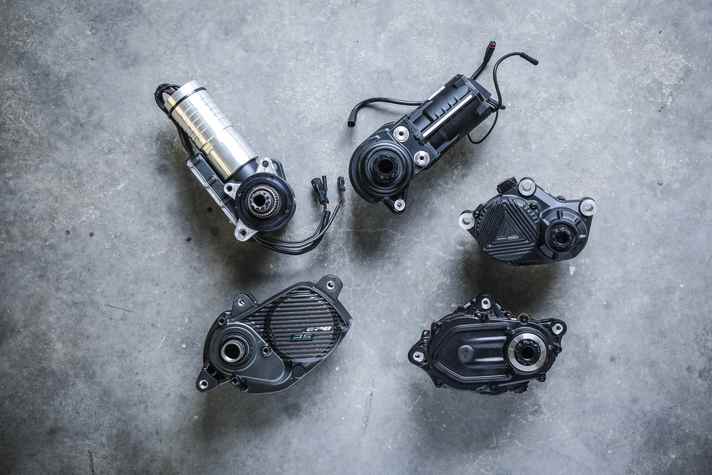 Die Motoren im Größenvergleich.  Maxon, Fazua und Forestal (oben, v.l.n.r.), sowie Shimano/Orbea und Specialized (unten, v.l.n.r.). Während Forestal, Specialized und Shiman0/Orbea auf klassische Bauformen setzen, stecken die E-Motoren bei Fazua und Maxon im länglichen Fortsatz räumlich getrennt vom Getriebe. Im Bike integriert wirken Maxon und Fazua dadurch besonders schlank.