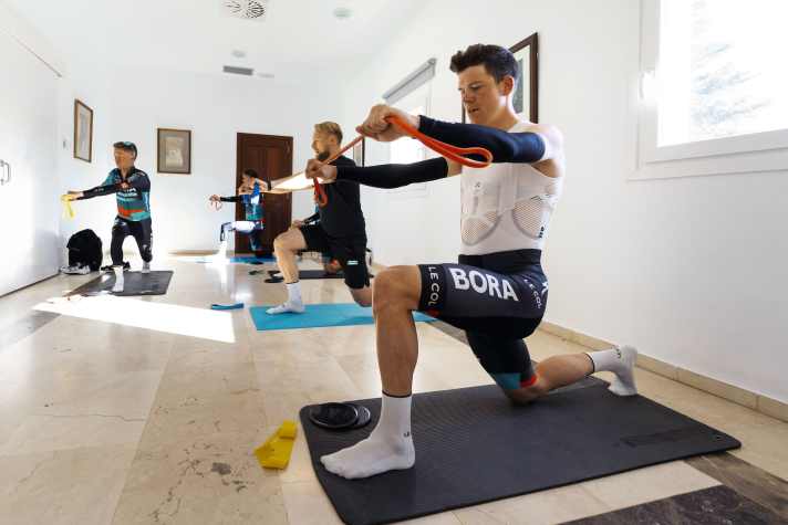 Osteopath Bartek Czerwinski bereitet die Rennfahrer um Bob Jungels (im Vordergrund) mit Übungen aufs eigentliche Training vor