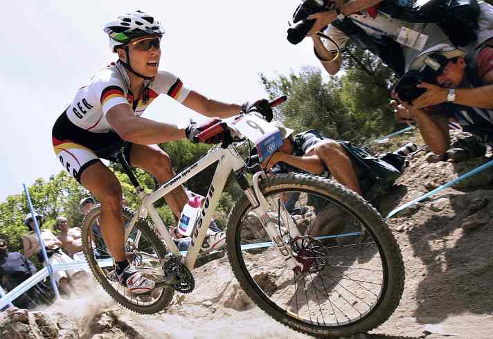   Athen 2004 stellte den ersten Wendepunkt in der Geschichte des Mountainbike-Sports dar. Erstmals war die Rennstrecke von technisch extrem fordernden Elementen geprägt. Lado Fumic brach damals der Sattel in so einer Schlüsselstelle. <a href="https://www.bike-magazin.de/hintergruende/interviews/athen-nachlese-interview-mit-sabine-spitz" target="_blank" rel="noopener noreferrer nofollow">Sabine Spitz holte mit Bronze ihre erste Olympia-Medaille</a> .