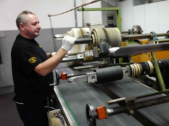   Spulen, Laufbänder, Wickelmaschinen: Die meterbreiten Gummiplatten aus der Kalandermaschine werden auf die benötigten Breiten portioniert und wieder aufgerollt.