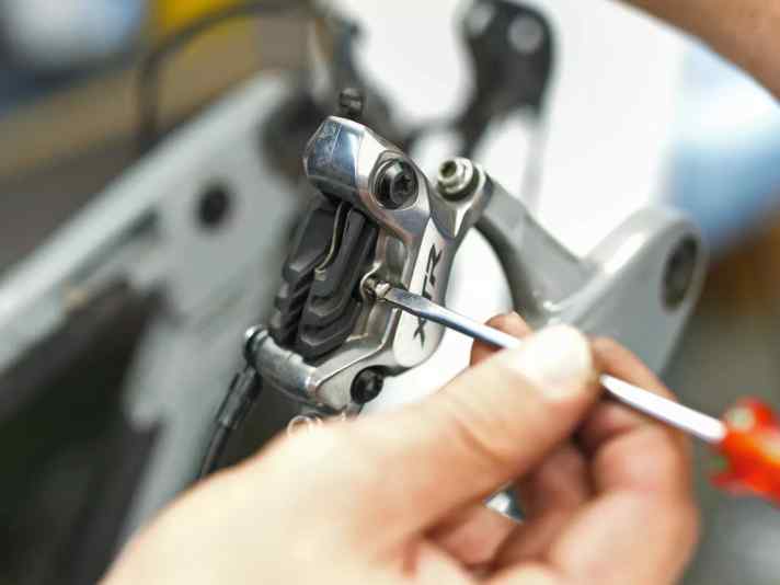 Sicherungsschraube oder Splint entnehmen, Beläge nach oben aus dem Bremssattel nehmen. Die Trägerplatte darf nie Kontakt zur Bremsscheibe bekommen.