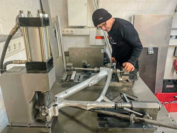 Jürgen Schlender bringt auf der Rahmenlehre alles Stellung. Später soll unsere 29er-Mountainbike 160 Millimeter Federweg hinten haben. Der Hinterbau ist ist auf 27,5 Zoll ausgelegt (MX oder Mullet genannt), weil Alutech so auf Carbonstreben verzichten kann, die wiederum aus Fernost importiert werden müssen. So schweißt auch diese Streben der Chef persönlich. | h.