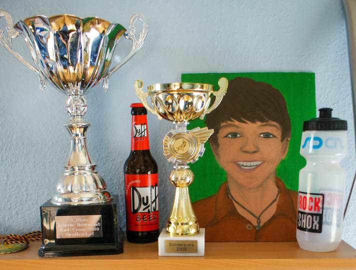 Stillleben mit Selbstporträt: 2010 war das Regal im Kinderzimmer von Georg noch spärlich mit Trophäen gefüllt. Was sich schon in den folgenden Monaten rasant änderte. Die Bierflasche war übrigens nie zum Durstlöschen gedacht, sondern eine Hommage an Homer Simpson aus der TV-Kultserie "Die Simpsons", der sich bekanntlich gerne an Bier der Marke Duff labt.