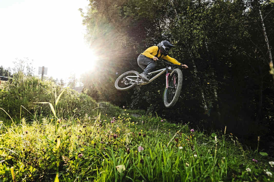 Lass fliegen! Das Propain Spindrift in der Doppelbrücken-Variante im lowlevel flyby auf der UCI Downhillstrecke im Bikepark Leogang.