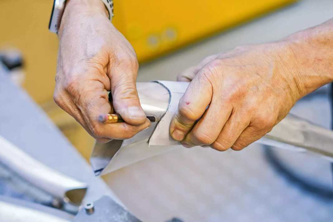 Mit Bleistift und Schablone zeichnet Jürgen Schlender die Schnittkanten an. Ähnlich, wie es ein Schneider mit Stoffen macht. Entlang der Linie schneidet er das Rohr dann mit der elektrischen Hand­säge in Form.