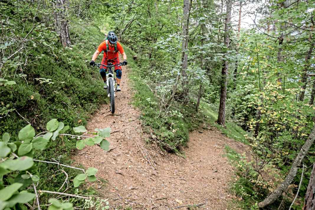 Mit Nachdruck in die Kurve: An dieser Stelle mag man sich fragen, was das mit E-MTB-Fahrtechnik zu tun hat. Aber eine ganze Menge! Den Unterschied machen das Mehrgewicht und der tiefe Schwerpunkt. Das bedeutet etwas Umstellung in Kurven, die so eng sind, dass man das Hinterrad versetzen muss.
 Das Anlupfen des Hinterrades vergleiche ich mit dem Spielchen, die hinteren beiden Stuhlbeine eines Stuhls anzulupfen, während man die Lehne nach vorne drückt. Und genau das ist der entscheidende Punkt. Je mehr man die Sitzfläche entlastet, desto einfacher fällt das Führen mit der Lehne.
 Aufs Bike übertragen: Je stärker der Impuls nach vorne die Pedale entlastet, desto leichter fällt das Führen mit dem Lenker. Angefahren wird die Kurve von außen nach innen (Bild 1).