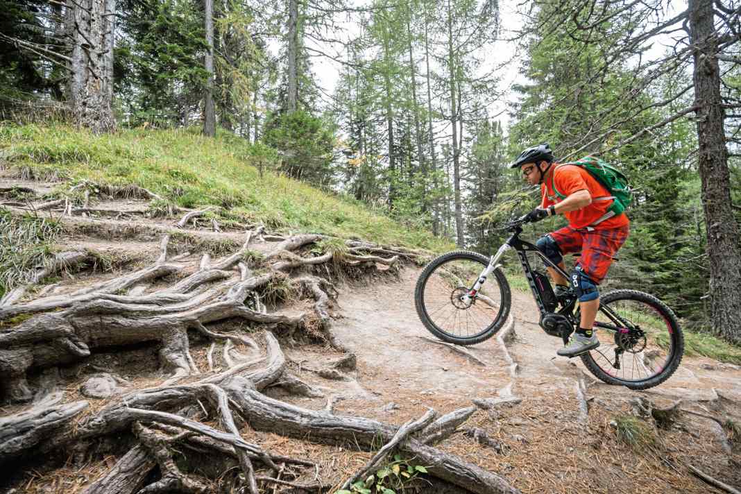 Wie mit dem Aufzug nach oben: Beim steilen Hindernis bergauf kommen wieder die schon vielfach erwähnten Grundsätze des Pedal-Managements zum Einsatz. Genau wie beim Hindernis im leichten Terrain, muss die Pedalabfolge angepasst werden und geländeoptimiert stimmen. Die Kunst, bei hohen Hindernissen ist es, mit der zusätzlichen Kraft des Motors umzugehen, denn der Bewegungsablauf beginnt im Stehen. Dabei muss man schauen, wie man die Motorkraft dosiert, um das Hinterrad nicht durchdrehen zu lassen. Hierbei ist die Wahl der richtigen Unterstützungsstufe sehr entscheidend.
 Bei sehr gutem Grip bietet sich der Turbo-Modus an. Wenn's aber rutschig wird, kommt dieser schnell an seine unzähmbaren Grenzen, und man muss in den Sport-Modus oder in den Tour-Modus gehen. Der eigentliche Bewegungsablauf beginnt eine Radlänge vor dem Hindernis in einem Gang, wo man etwa eine Radlänge mit einer halben Pedalumdrehung zurücklegt. Von der Körperposition her ist man bei dieser Technik tendenziell weit vorne und hat somit eben weniger Druck am Hinterrad, um die Traktion auf den Boden zu bekommen (Foto 1 und 2) ...