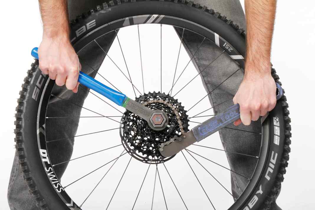 1 Kassette demontieren: Die Demontage der Kassette ist bei Sram und Shimano gleich. Am besten stehen Sie hinter dem Laufrad. Von oben haben Sie den besten Hebel. Legen Sie die Kettenpeitsche auf eines der Ritzel, der Hebel zeigt nach links. Setzen Sie den Zahnkranzabzieher in die Kassette ein und öffnen Sie den Verschlussring (bzw. die Kassette bei Sram) gegen den Uhrzeigersinn.