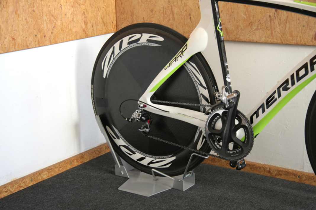 Stellen Sie Ihr Rennrad zu Hause in einem geeigneten Fahrradständer ab. Die früher üblichen Dreibeinständer zerkratzen voluminöse Rahmenrohre. Besser geeignet sind Ständer, die das Hinterrad aufnehmen. Kontrollieren Sie bei längeren Standzeiten regelmäßig den Reifendruck.