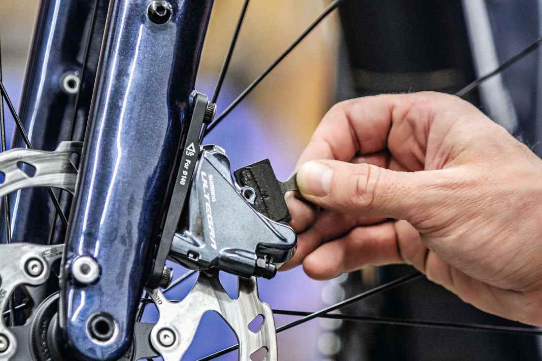 Verölte Beläge lassen Rennrad-Scheibenbremsen quietschen, sie müssen ausgetauscht werden: ­Sicherungssplint und Schraube entfernen – dann können die Beläge einfach nach oben herausgenommen werden.