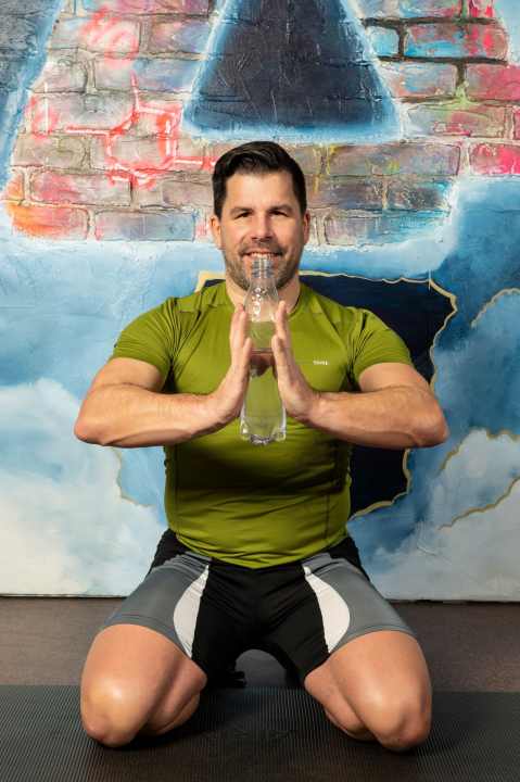 Kräftigungsübung für Schulter, Brust und Trizeps: PET-Flasche zusammendrücken und halten.