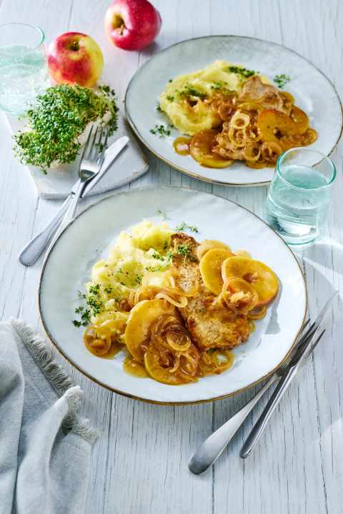 Herbstliches Schweineschnitzel mit Apfel kommt mit Röstzwiebeln und Kartoffelbrei besonders gut.