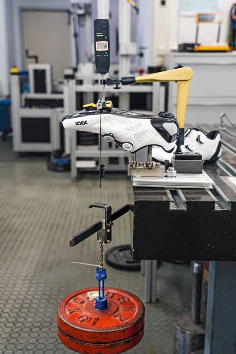 Rennradschuhe im Test: 200 Newton, also etwa 20 Kilo Zug, bringen die beiden 
Hantelscheiben als Druckkraft auf die Sohlen. Die steifsten Exemplare geben kaum einen halben Millimeter nach.