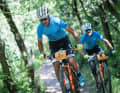 Zwei Fahrer, ein Team: Bei der BIKE Transalp wird traditionell als Duo gefahren. Inzwischen gibt es aber auch Solo-Klassen. Hier kämpfen die Costa Ricaner Jonathan Carballo Ramirez und Dax Jaikel Arce, der mit Unterschenkel-Prothese fährt, um die blauen Führungstrikots der Masters-Wertung