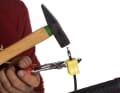 Schieben Sie nun die Schutzkappe, die Befestigungsschraube und den Klemmring in dieser Reihenfolge auf die Leitung. Legen Sie die Bremsleitung zwischen die gelben Klemmbacken und fixieren Sie diese mit einer Rohrzange. Danach schlagen Sie die Stützhülse mit einem Hammer vorsichtig in die Leitung ein.