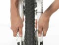 5. Stellen Sie das Bike auf eine ebene Fläche. Wenn möglich, nicht an einem Hang oder auf gerölligem Untergrund montieren. Kontrollieren Sie den richtgen Sitz der Nabe, indem Sie Federgabelholme und Sitzstreben mit beiden Händen Richtung Boden drücken. Dadurch rutscht der Nabenflansch exakt in die Ausfallenden.