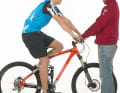 2. Setzen Sie sich in zentraler Position auf Ihr Bike, so dass der Druck auf Sattel und Lenker lastet. So messen Sie, wie weit die Gabel einfedert. Eine zweite Person sollte das Bike dabei halten.

3. Durch Ihr Gewicht rutscht der Kabelbinder am Gabelholm nach oben und zeigt den Negativ-Federweg (Sag) an – der Federweg, um den die Gabel ausfedert, wenn Sie z.B. eine Stufe hinunter fahren.