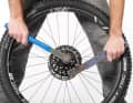1 Kassette demontieren: Die Demontage der Kassette ist bei Sram und Shimano gleich. Am besten stehen Sie hinter dem Laufrad. Von oben haben Sie den besten Hebel. Legen Sie die Kettenpeitsche auf eines der Ritzel, der Hebel zeigt nach links. Setzen Sie den Zahnkranzabzieher in die Kassette ein und öffnen Sie den Verschlussring (bzw. die Kassette bei Sram) gegen den Uhrzeigersinn.