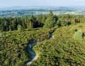 Cityspot Ticknock: unten die Stadt, dahinter das Meer, oben ziehen sich feinste Trails durch die Heidelandschaft.