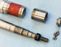 Lagerleben im Detail: Das hier abgebildete Shimano-Achslager ist bewährt langlebig und zudem austauschbar. In der eingeschraubten Alu-Hülse (oben links) sitzt ein großes Lager aus Spezialpolymer, in dem sich die polierte Achse (unten links) dreht. Auf ihr äußeres Ende ist eine Metallhülse (oben Mitte) geschraubt, in deren beiden Enden sich zwei Kugelläufe für lose Lagerkugeln (unten rechts) befinden. Sie werden vom Schraubkonus (oben rechts) und dem Achskonus am Platz gehalten. Diese Konstruktion erlaubt relativ große und damit robuste Lagerbauteile. Wer will, könnte sie nachjustieren.