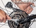 Stellen Sie noch einmal sicher, dass Achse und Bremsscheibe sauber und ohne zu verkanten im Hinterbau sitzen und die Nase der Drehmomentabstützung in die Öffnung der Ausfallenden greift. Drehen Sie dann beide Achsmuttern handfest zu. Ziehen Sie die Muttern abschließend mit zwei Schlüsseln gleichzeitig endgültig fest.