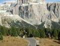 Dolomiten-Klotz: Ameisengleich klettern Radler vor den mächtigen Wänden der Sellagruppe von Süden zum Sellajoch. Hinten links: der Piz Boé (3152 m).