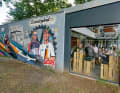 Kölsche Helden: Das neue Graffiti an der Bude zeigt Kölns Rad-Heroen Rolf Wolfshohl, Marcel Wüst und Nils Politt.