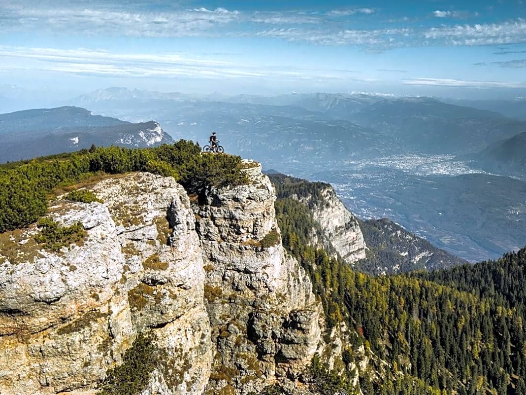 Der Roen ist mehr Hochplateau als Gipfel. Unten im Tal fließt die Etsch von der Landeshauptstadt Bozen im Norden Richtung Trentino. Dahinter erheben sich die Dolomiten mit Langkofel, Schlern und Latemar.