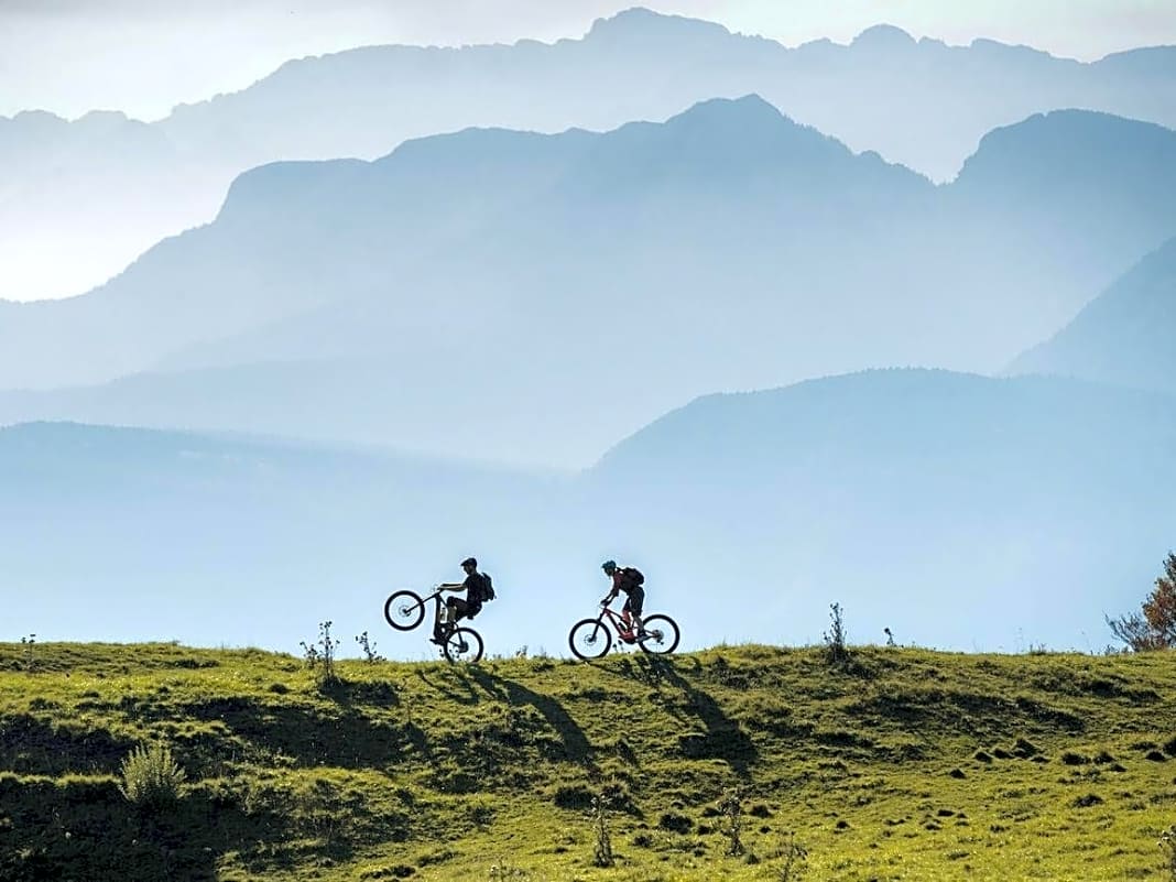 Panorama-Wheelie vor der Cisloner Alm: Die Steinhütte liegt im Naturpark Trudner Horn auf nur 1290 Metern. Von dem offenen Sonnenplateau blickt man über Südtirol hinweg direkt in die mächtigen Kolosse der Brenta-Dolomiten.