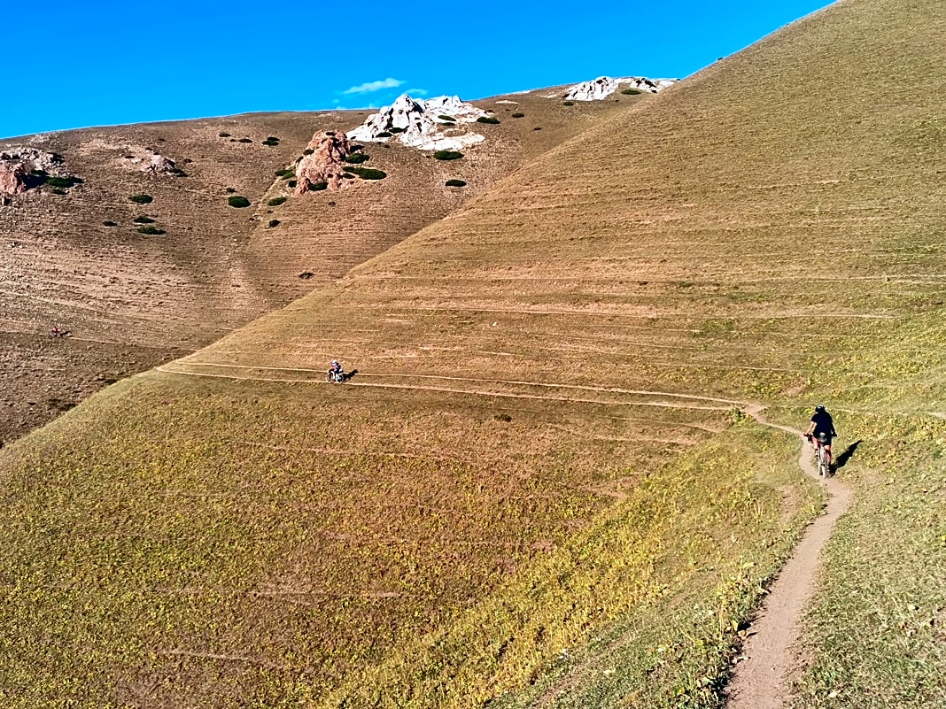 Einer der schöneren Singeltrails beim Silk Road Mountain Race. Nach drei Stunden Tragen und Schieben durch ein Tal gab es diese Belohnung. Gianluca Safuro fährt vor Jenny Tough in die Abendsonne.