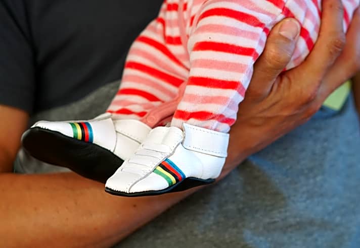   Nino Schurter hat eine Tochter, hier noch als Baby in Schuhen mit Regenbogenstreifen.